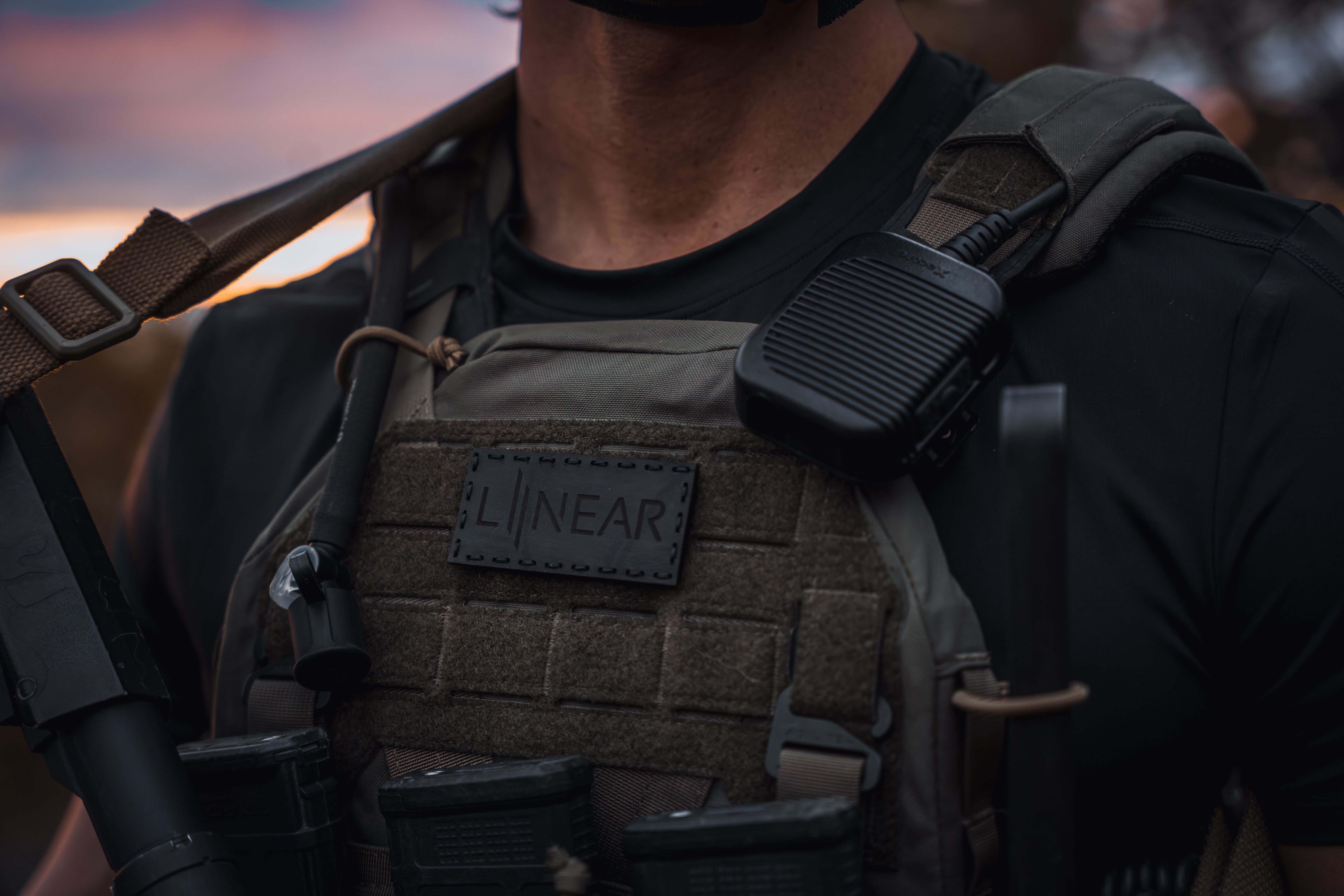 Person wearing a tactical vest with he LINEAR x Moral Decay Patchwork elite patch on a blurred background