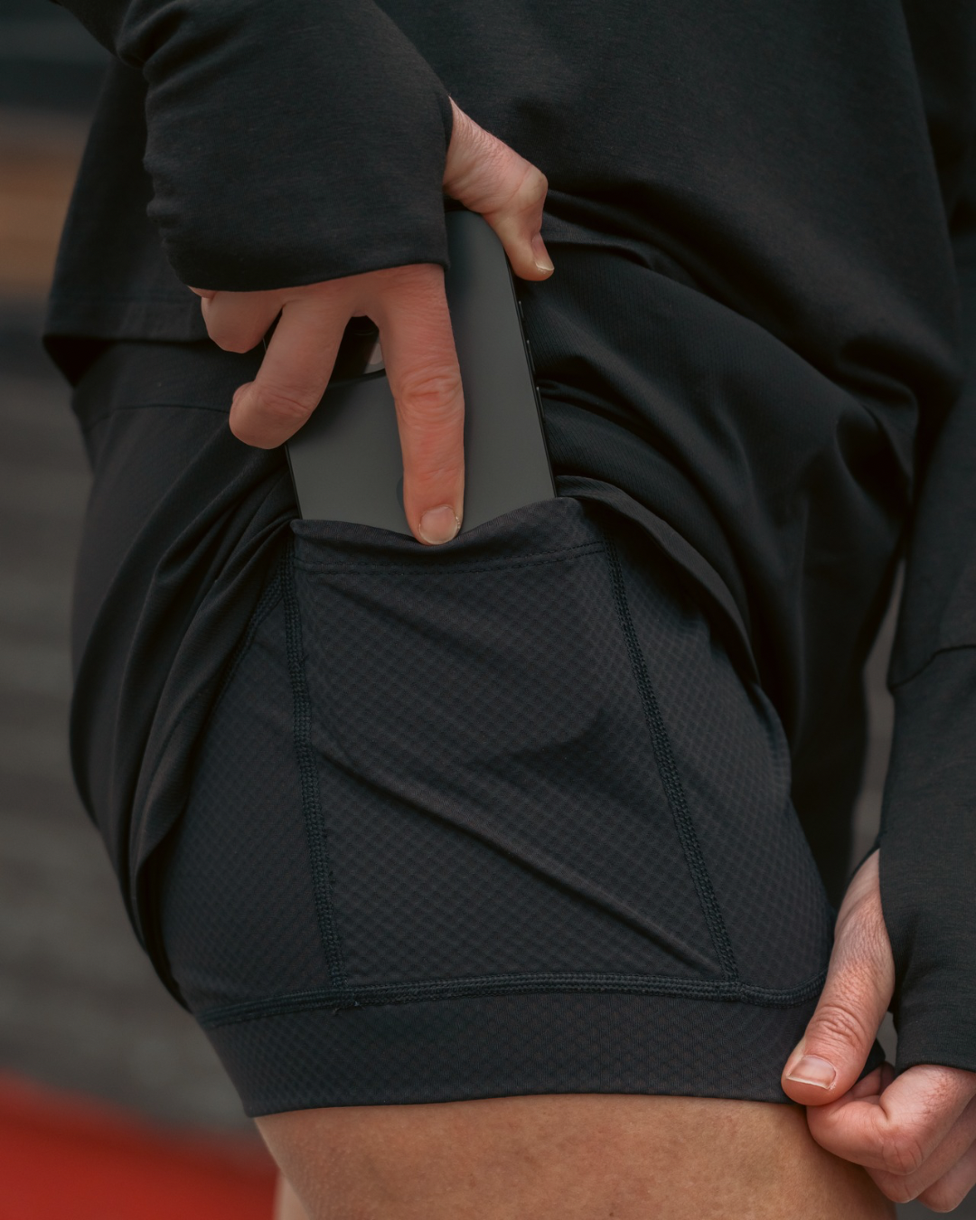 woman wearing black athletic shorts expressing liner with a pocket, holding a phone.