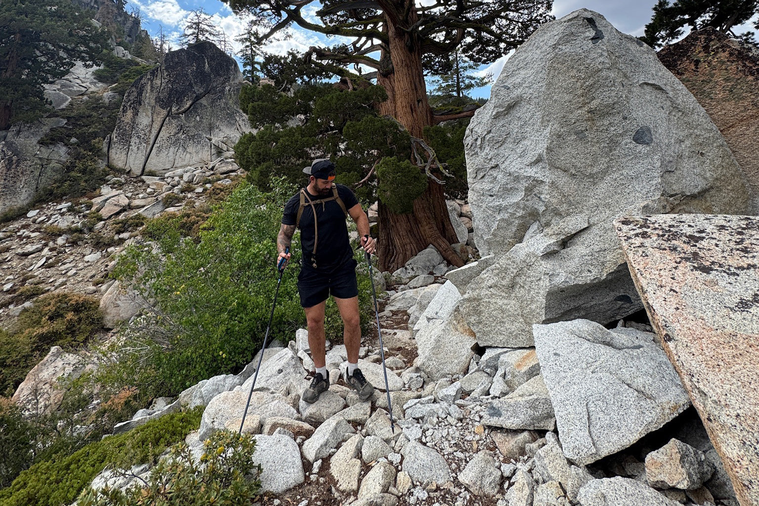 Navy SEAL Kyle Reed hiking on a rocky mountain trail with trees and clouds in the background