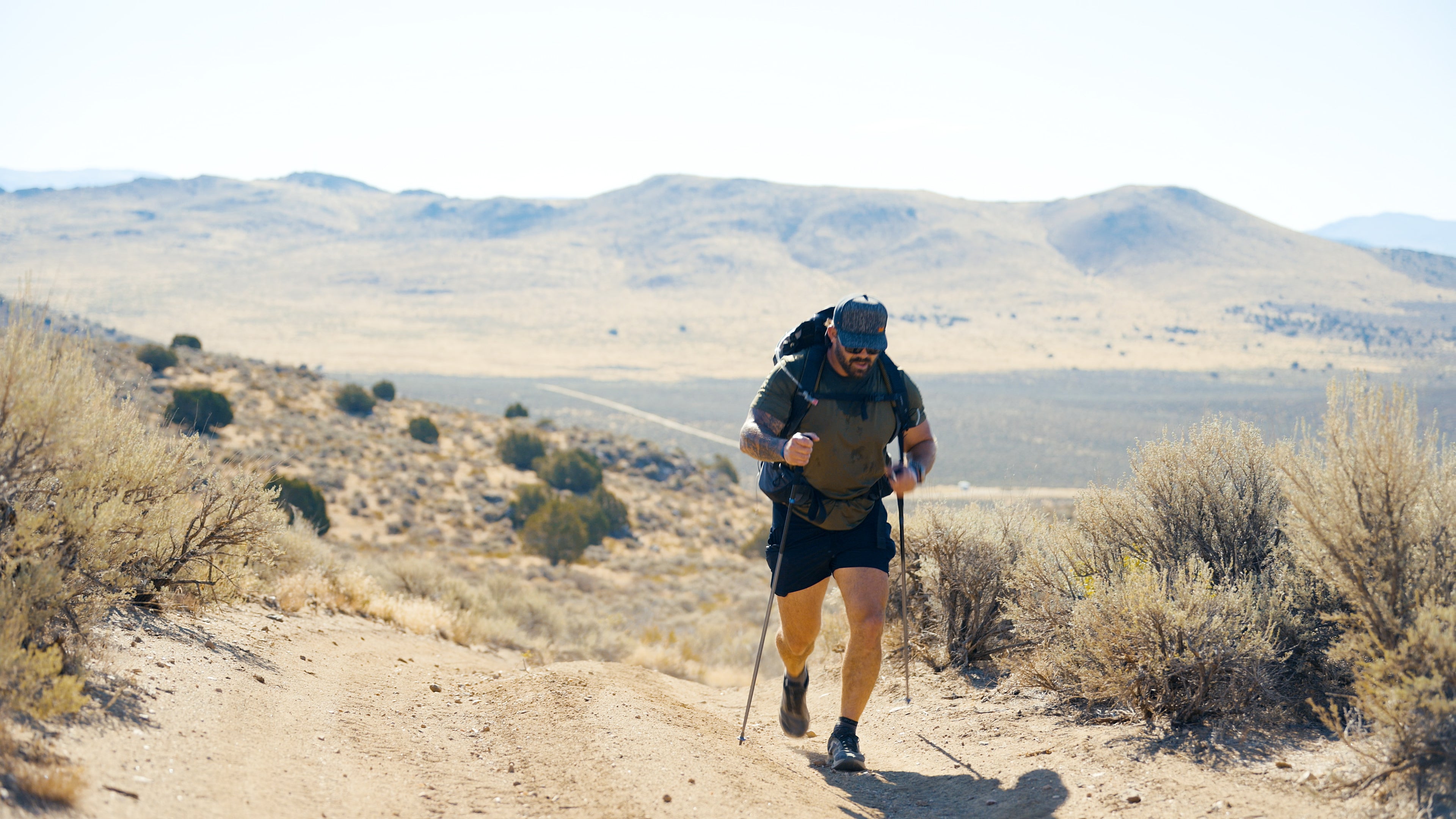 Navy Seal Kyle Reed hiking in a desert landscape with mountains in the background for the 20 Mountain 220.