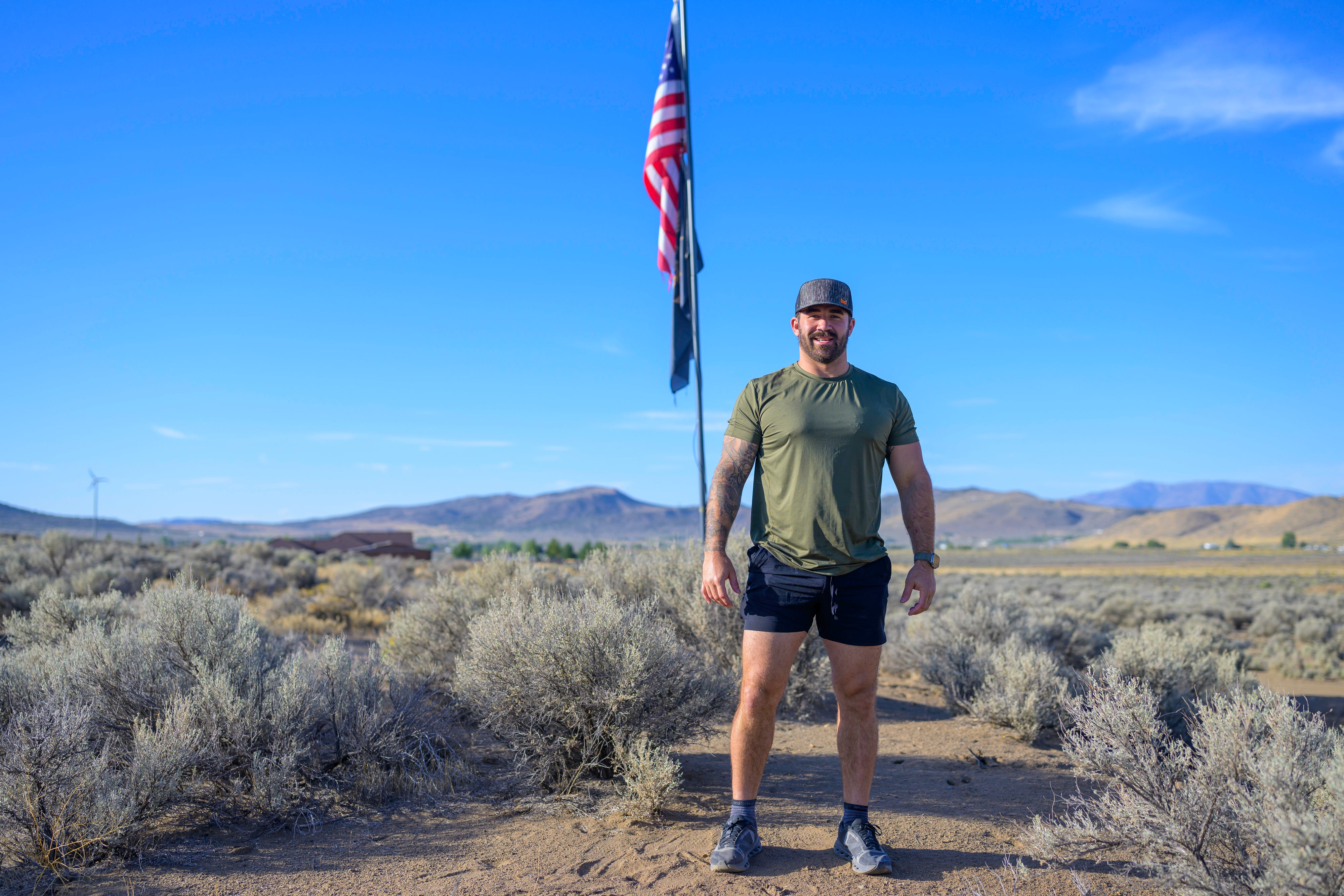 Navy Seal Kyle Reed standing in a desert landscape with an American flag
