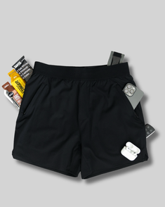 Black shorts with various items on a gray background