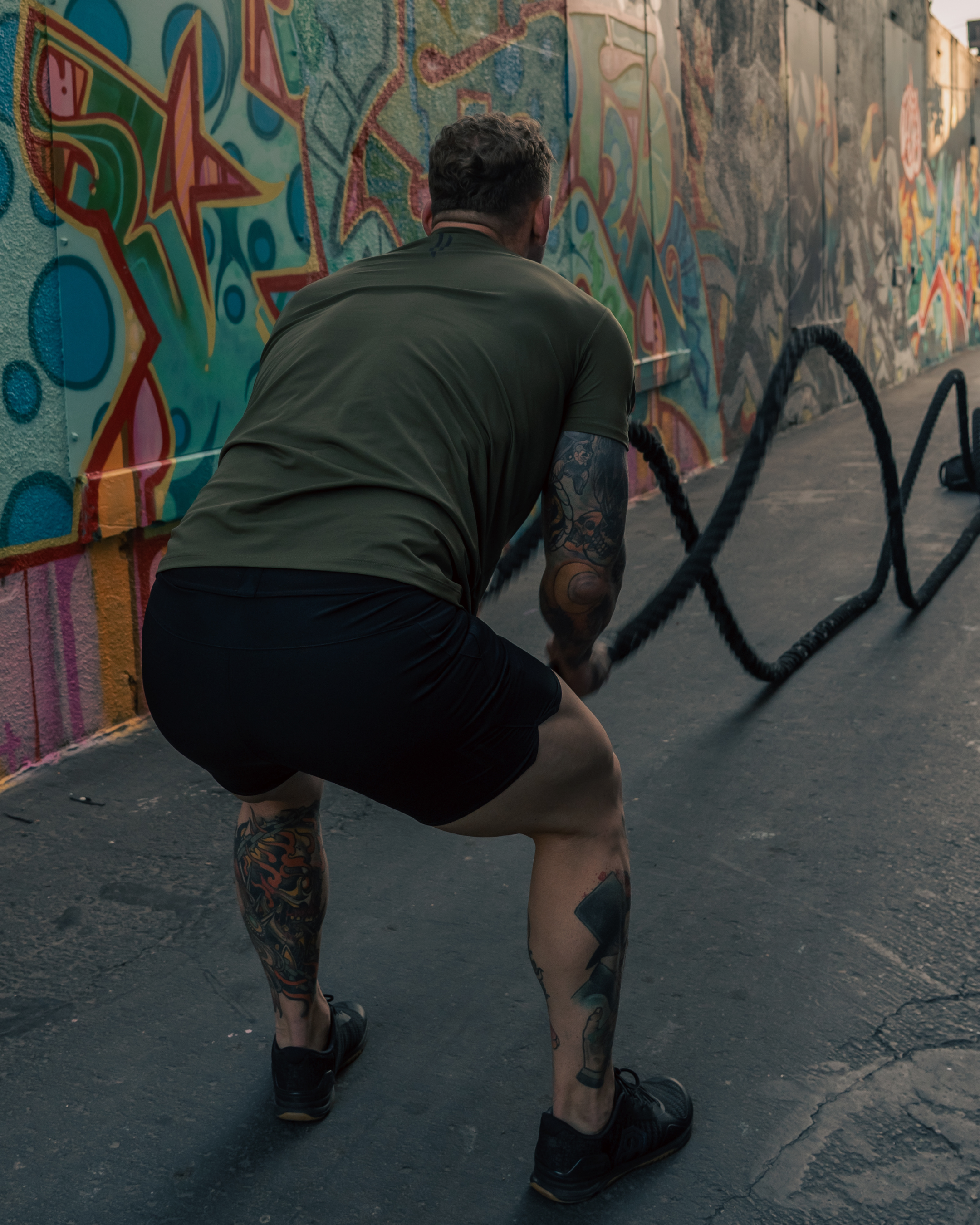 Person exercising with resistance ropes against a colorful mural.