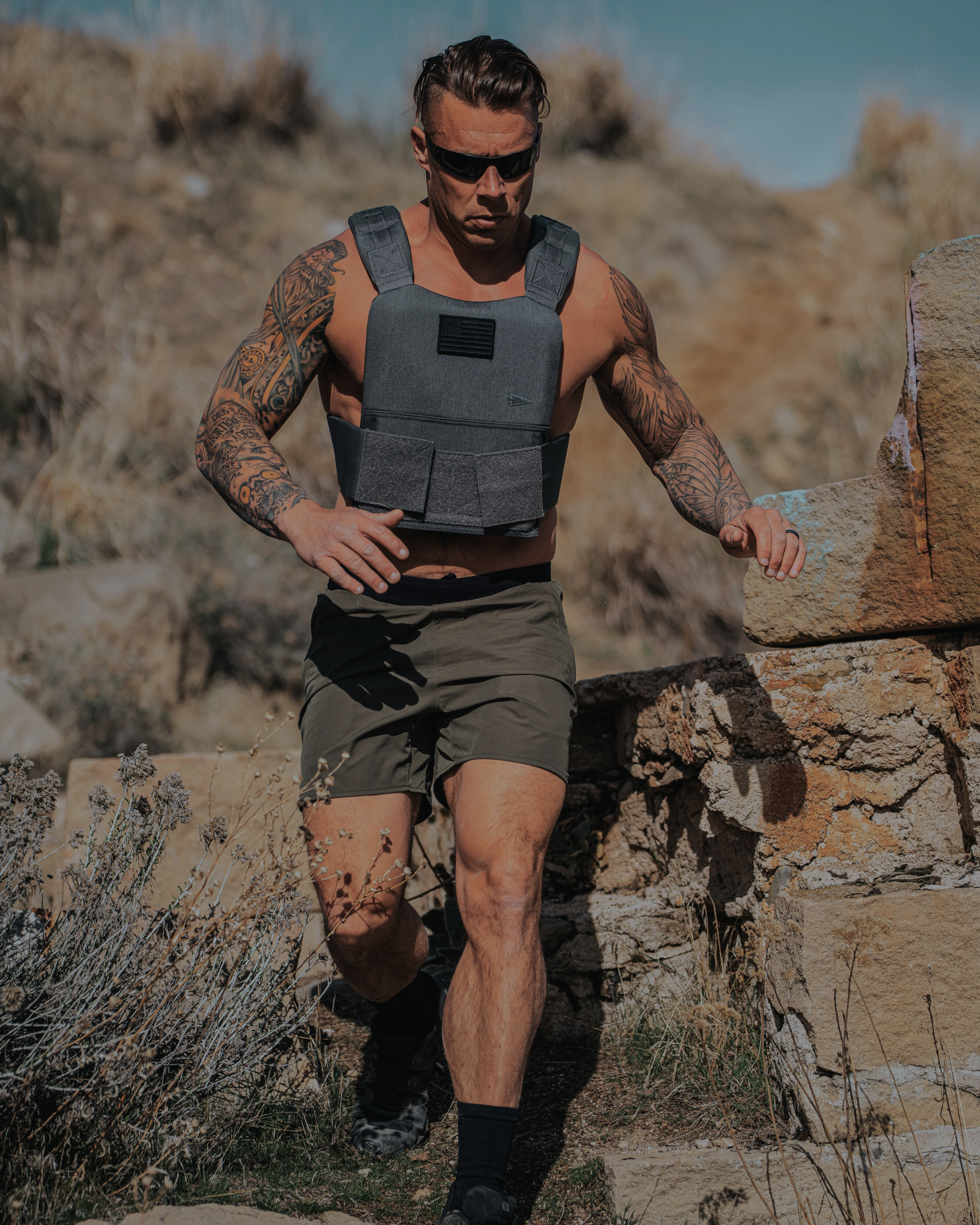 Man wearing a weighted vest and sunglasses in a desert setting