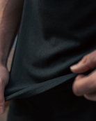 male wearing black drop cut crew shirt stretching black fabric