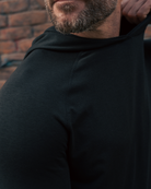 Man wearing a black hoodie with a brick wall background