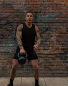 Man lifting a kettlebell against a brick wall