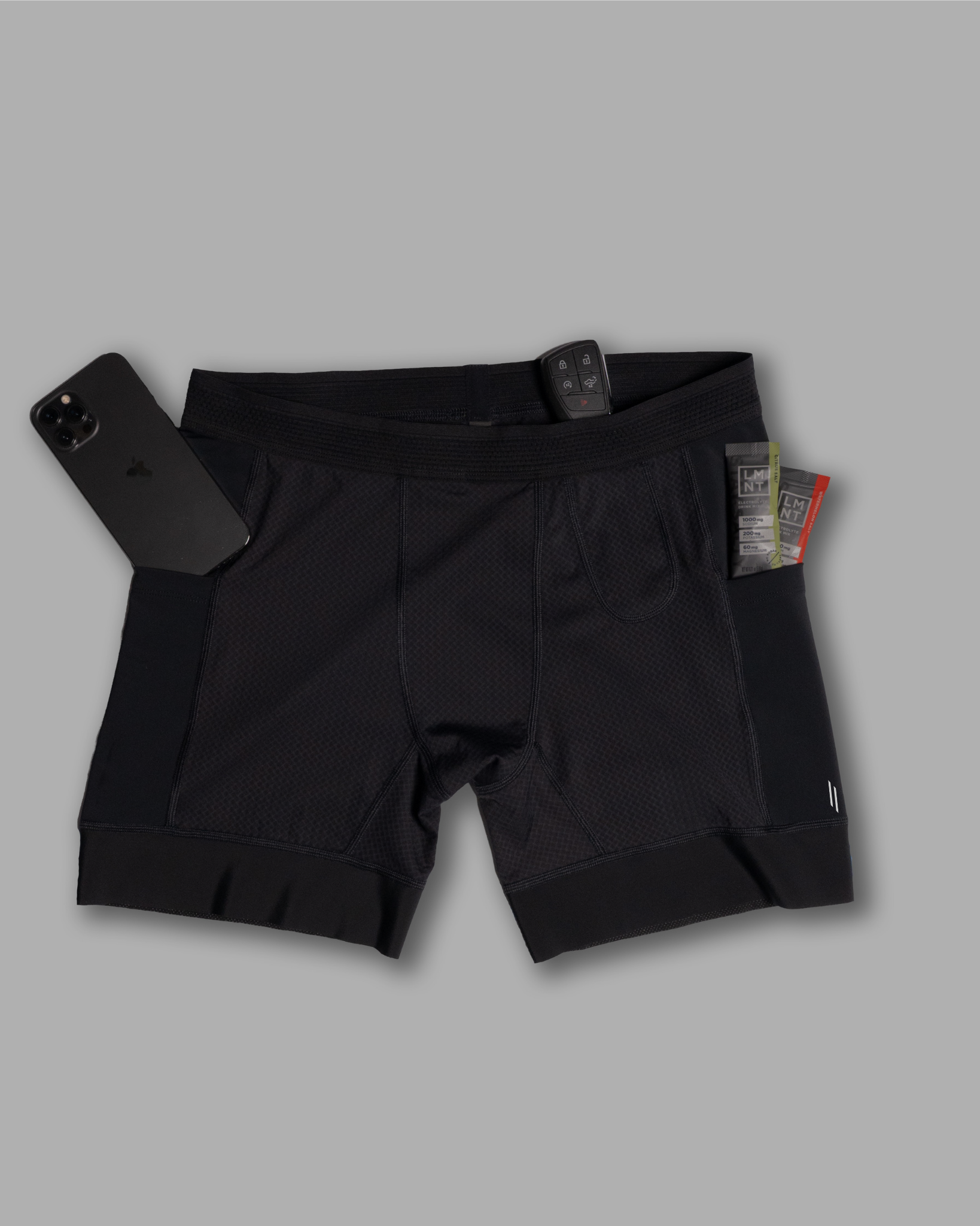 Black athletic shorts with a phone and tags on a gray background