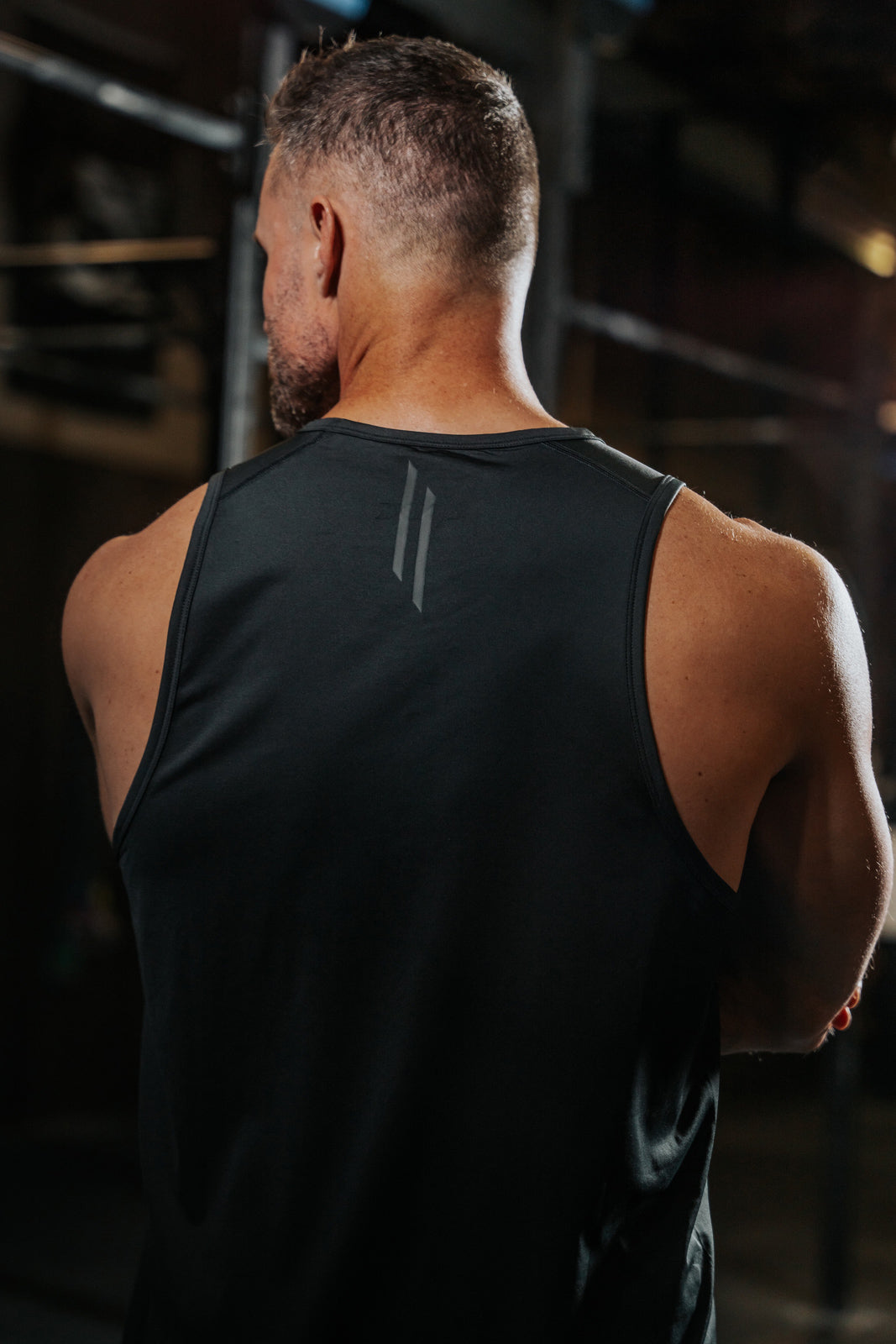 Man in LINEAR Baseline Series Night Ops Tank standing in a gym setting.
