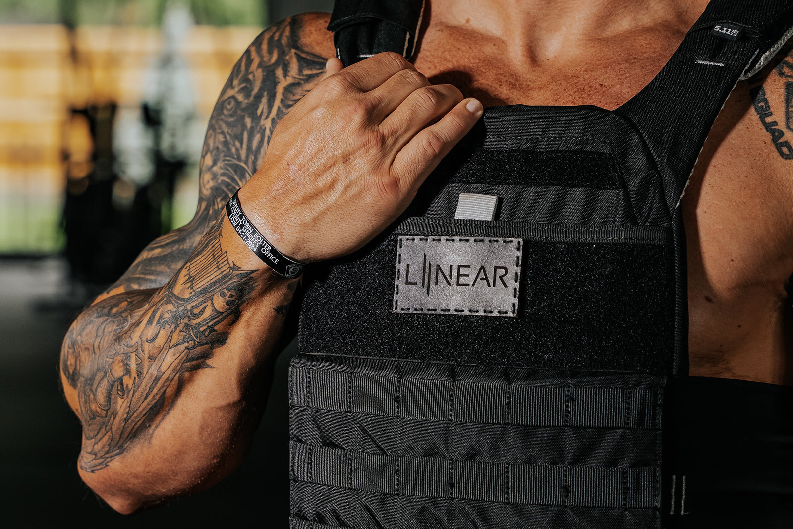 Person wearing a black weight vest with a visible LINEAR® Team patch in Night Ops Black in front of a stained glass window. 
