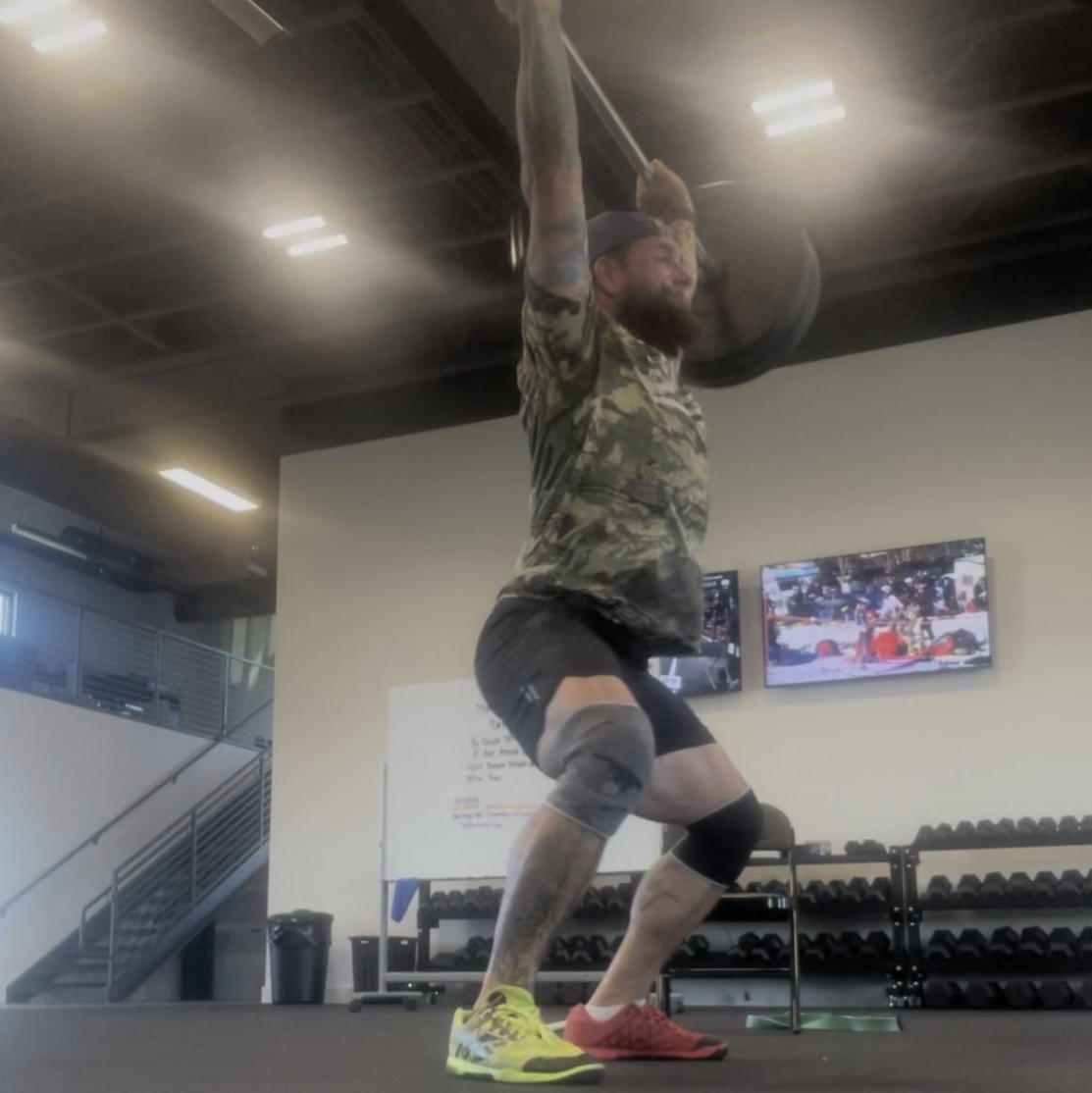 LINEAR® customer Brandon S performing a barbell press in a gym setting wearing the baseline series shorts in night ops black
