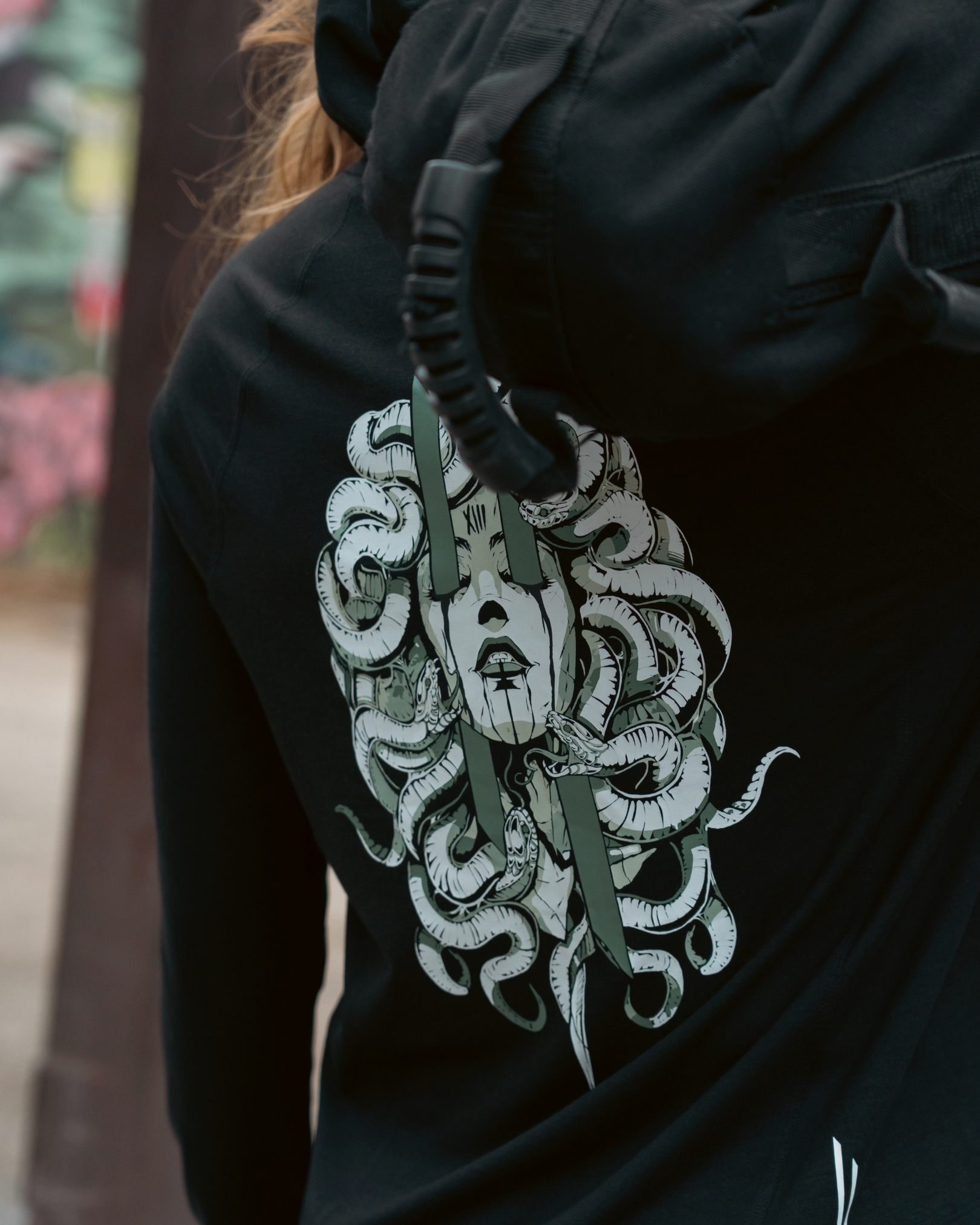 Black hoodie with a Medusa design on the back, worn by a person.