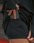 woman wearing black athletic shorts expressing liner with a pocket, holding a phone.