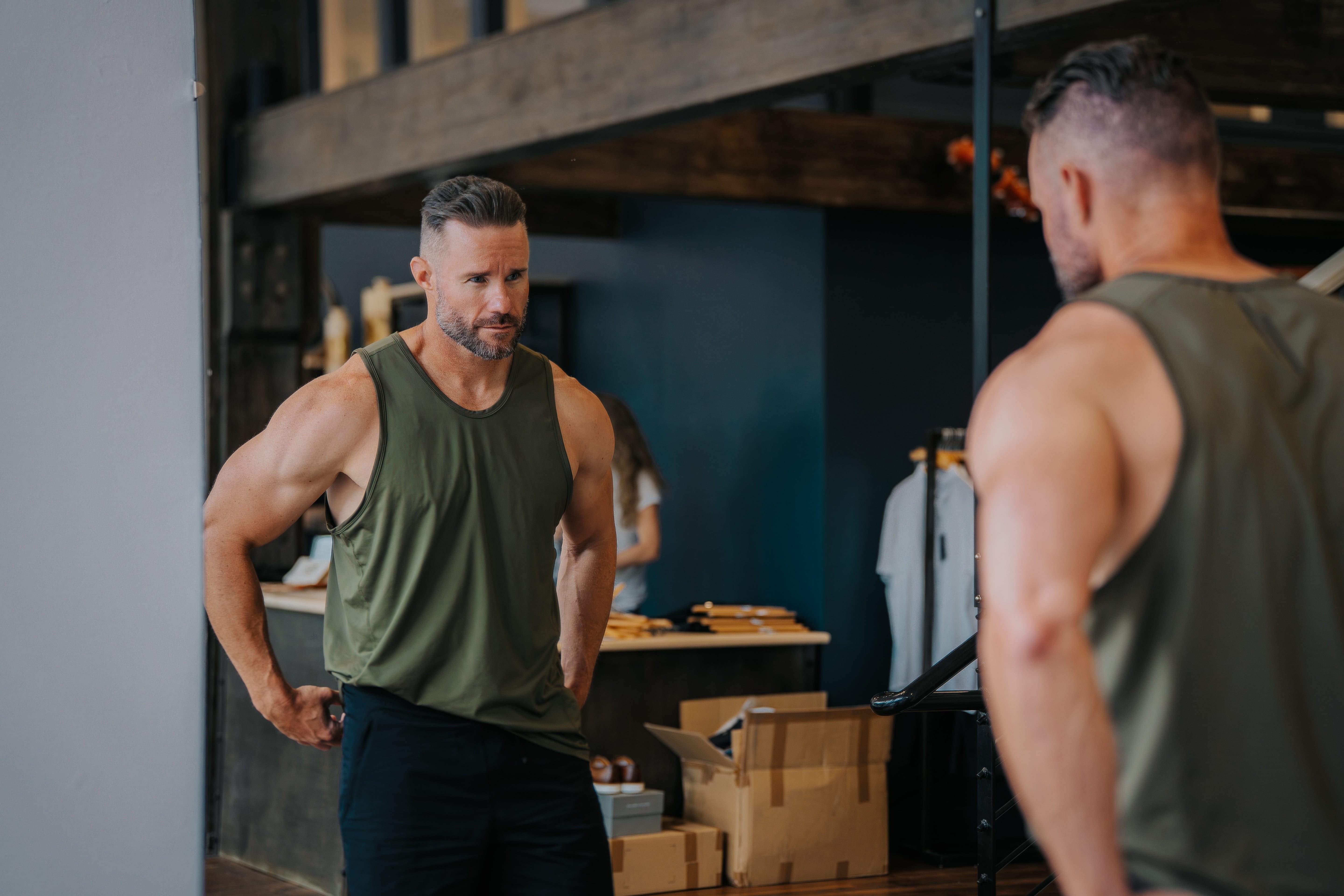 Man trying on a LINEAR Baseline tank in ODA Green in front of a mirror at the SALT For MEN clothing store in Boise Idaho