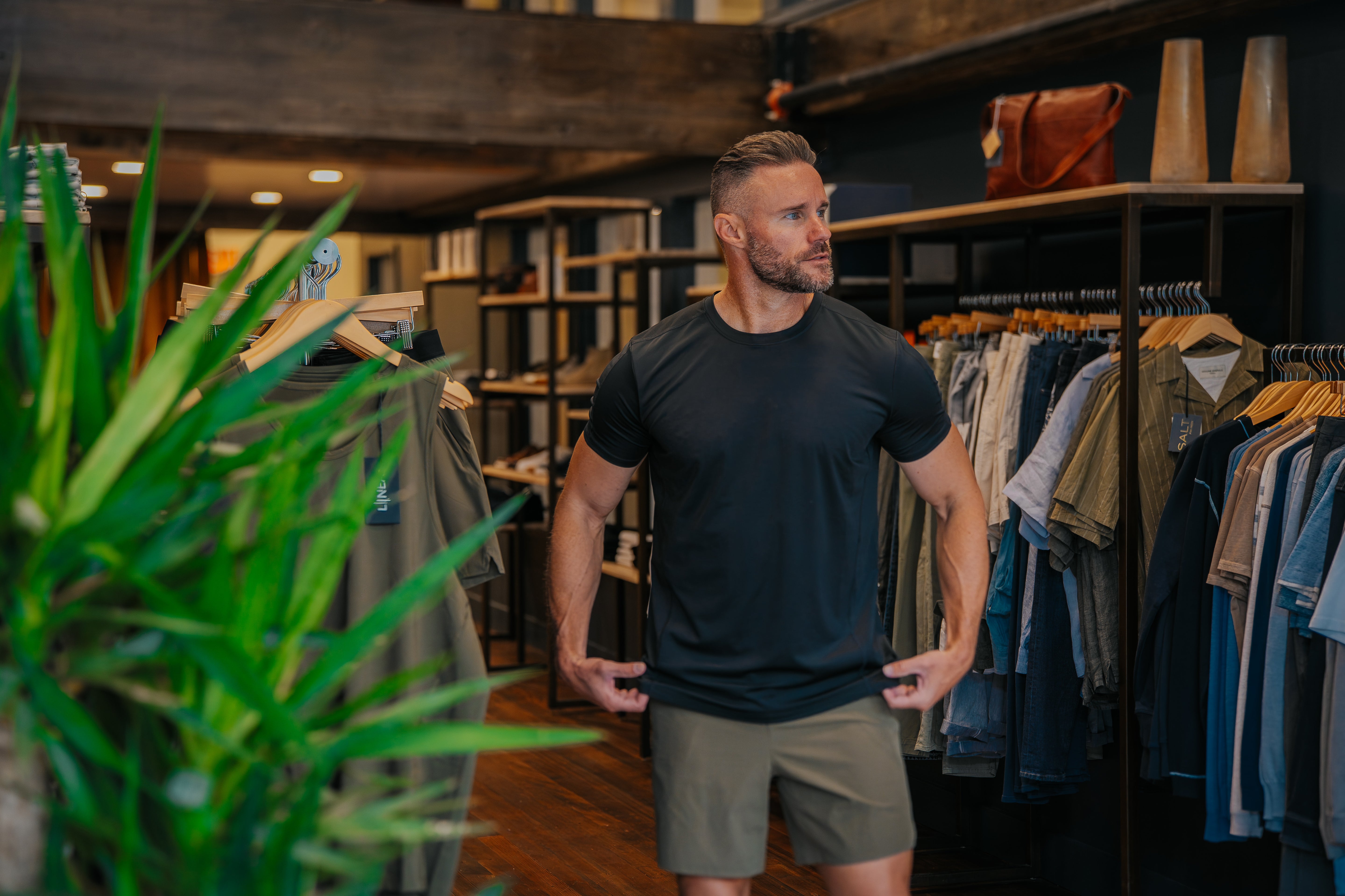 Man wearing a LINEAR Baseline shirt in Night Ops Black and Baseline Series Shorts in ODA Green at the SALT For MEN clothing store in Boise Idaho