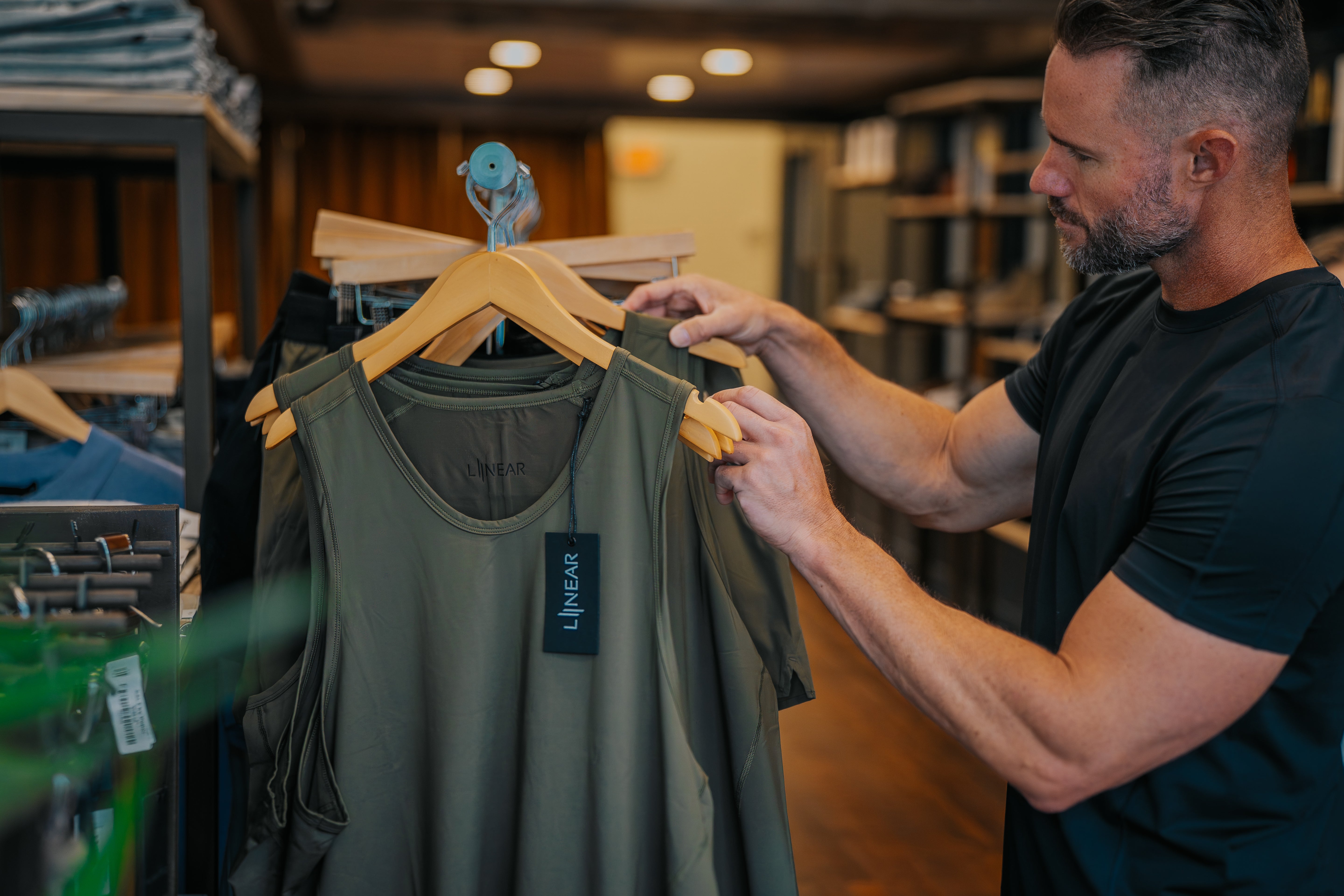 Man holding a LINEAR Baseline tank in ODA Green at the SALT For MEN clothing store in Boise Idaho