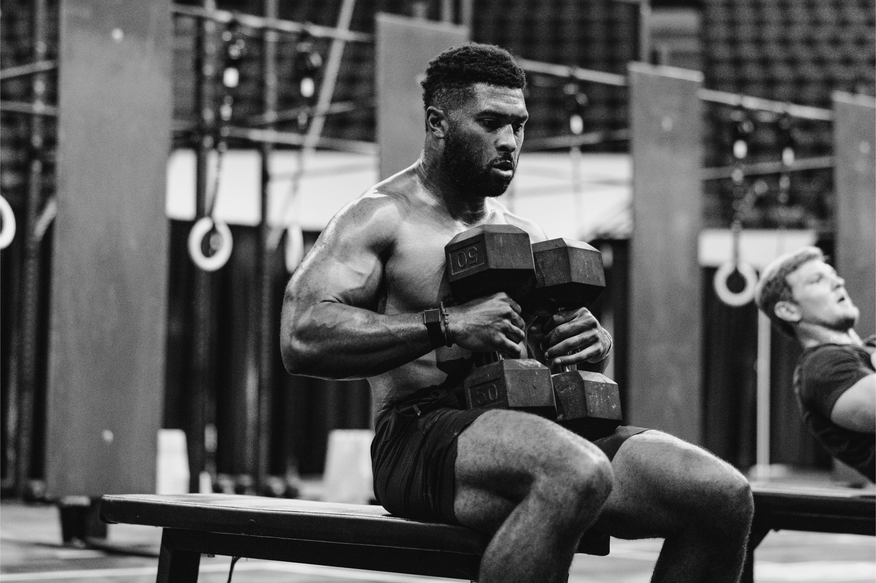 LINEAR athlete Kody Dickerson competing at the Magic City Games with dumbbells on a bench in a gym setting.

